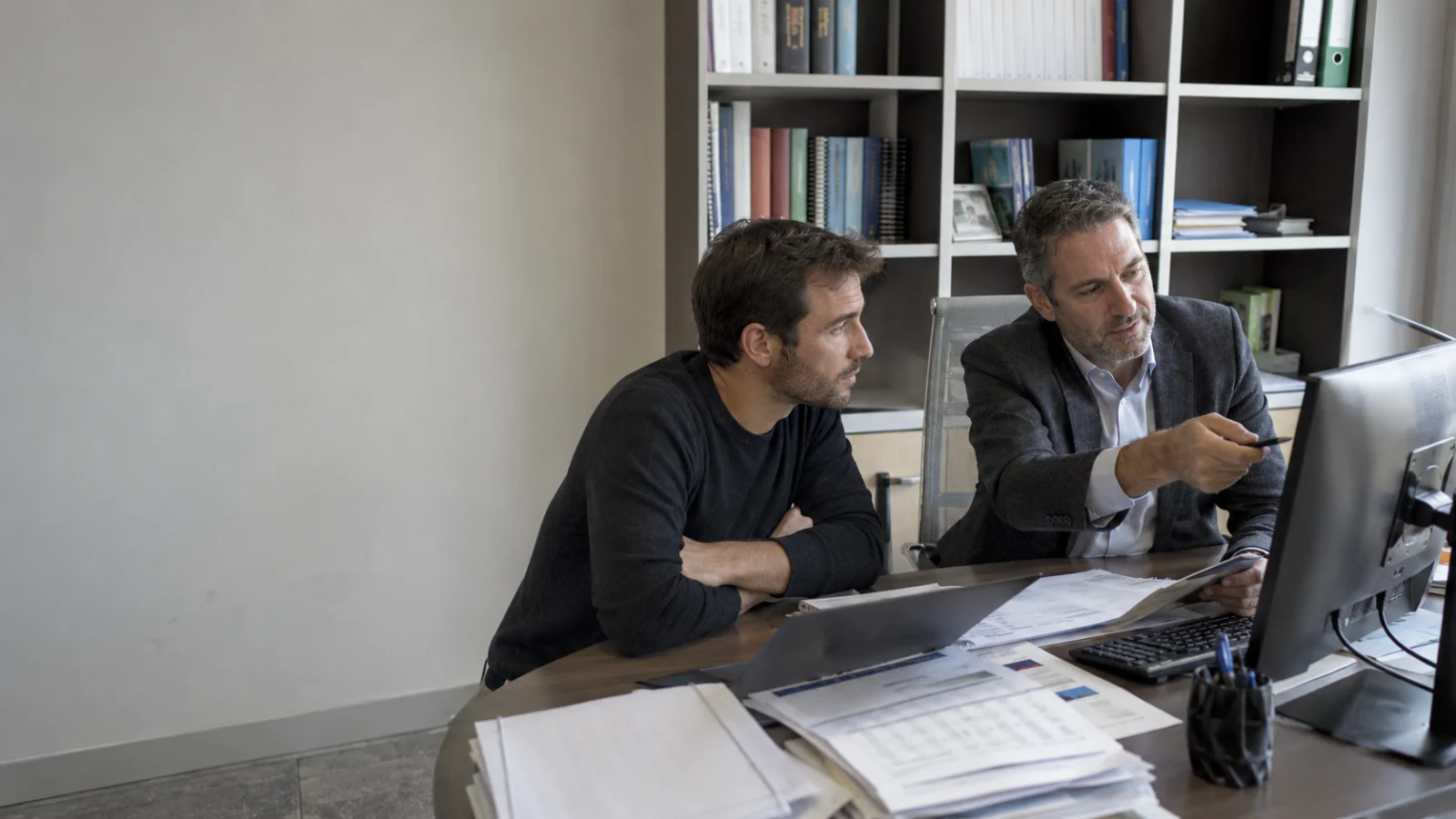 Un commercialista analizza dati e decisioni insieme al cliente davanti a uno schermo